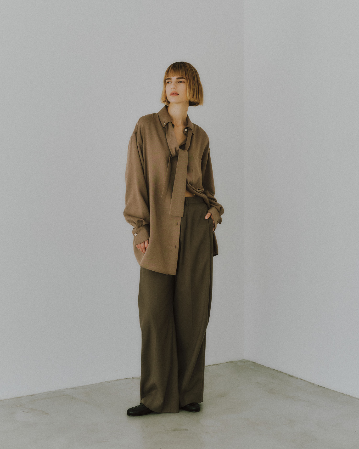 BROWN系のカシュクール2WAYシャツ、サイドタックスーツパンツを着用した女性