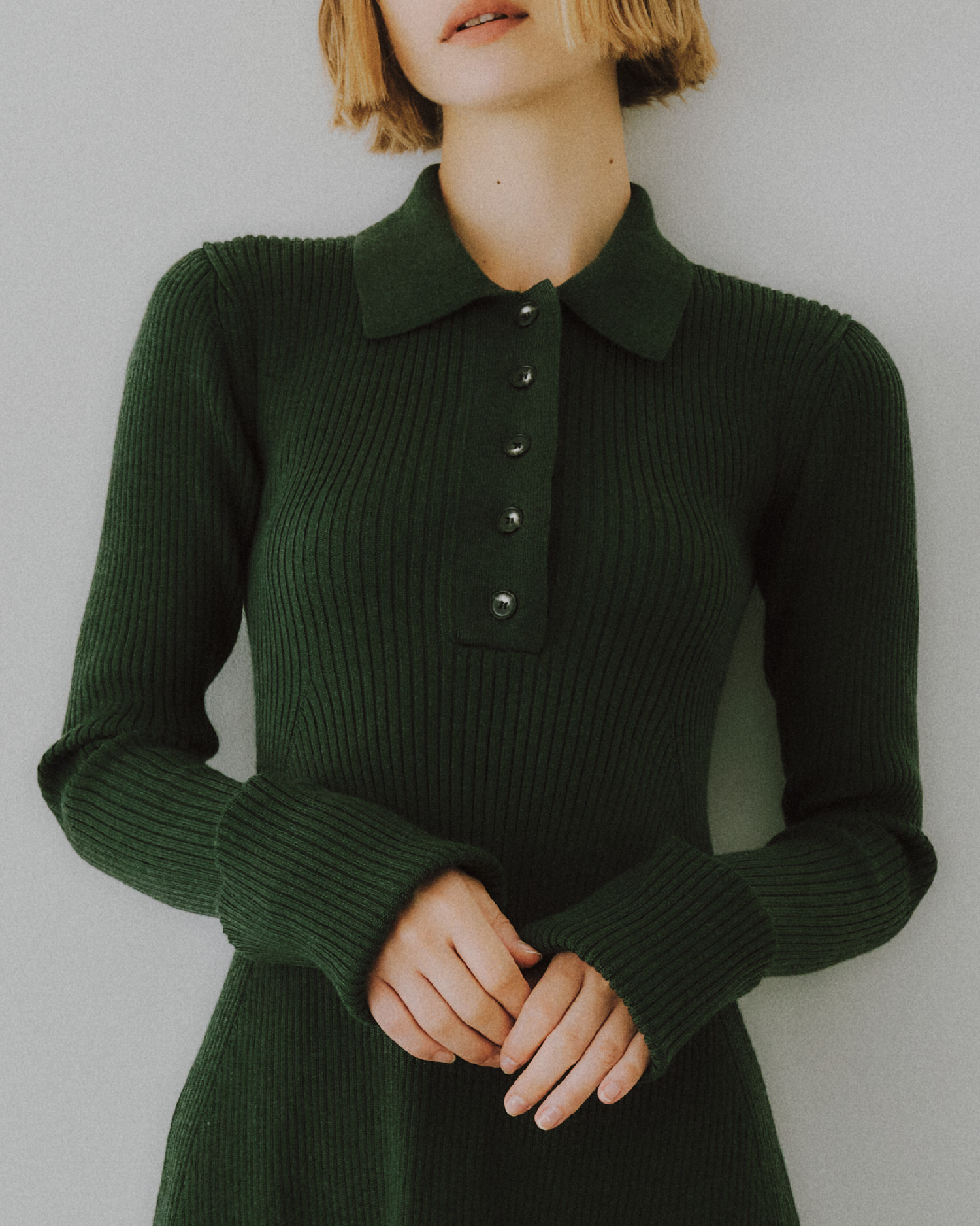 deep green色のヘンリーネックニットワンピースを着用した女性